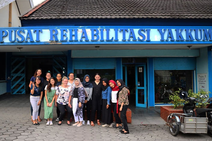 A group of volunteers and beneficiaries of YAKUUM posing in front of the YAKUUM rehabilitation building in Indonesia
