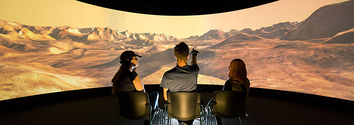 Student pointing at a curved widescreen projection of a simulated desert