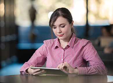 Female student in red-striped blouse using an iPad