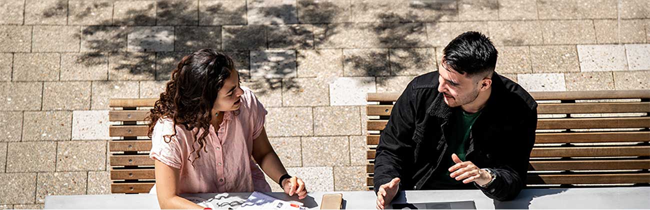 Student writes notes as another student discusses