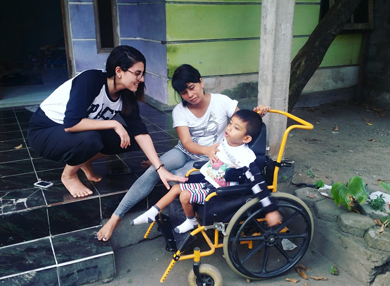 PACE alumni Leonie Nahhas with a child on a wheelchair and his caregiver in Indonesia.