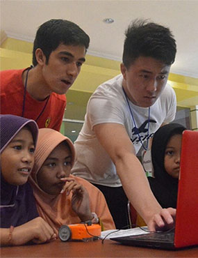 Students and Indonesian children looking at computer