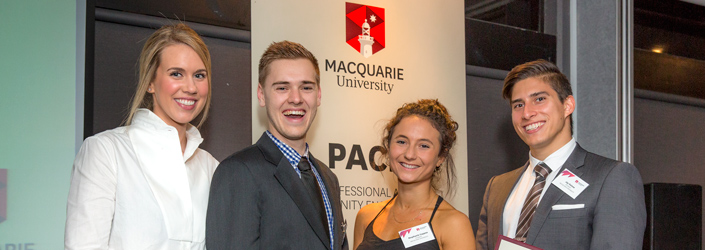 Four students dressed formally holding awards received at an evening presentation