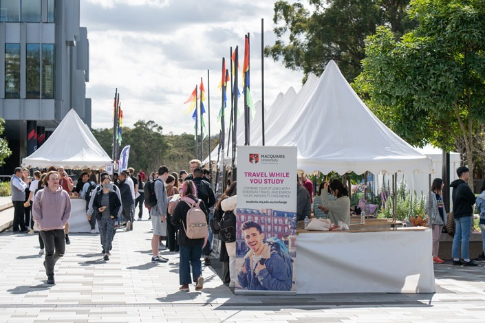 Stalls at the 2022 Exchange Fair at Macquarie University. Several students are walking to the stalls to ask for information.
