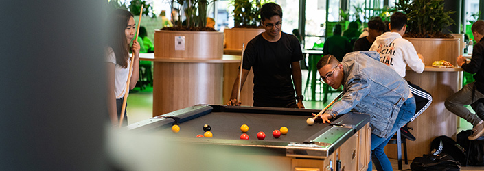 Three students playing a game of pool