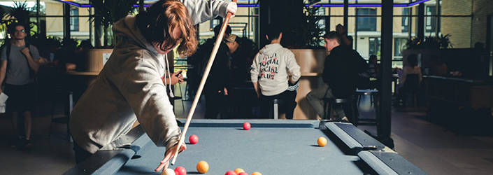 student playing pool with students sitting behind