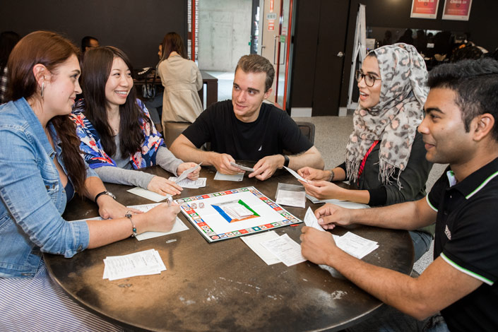 Students sitting around a table playing a board game